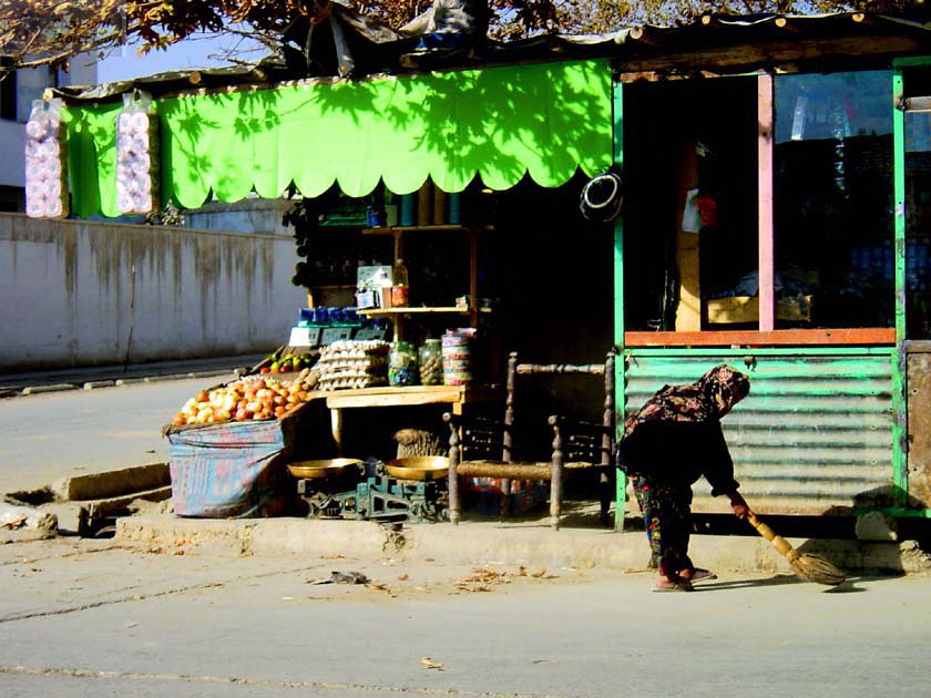 Little Girl sweeping in front of Shop 